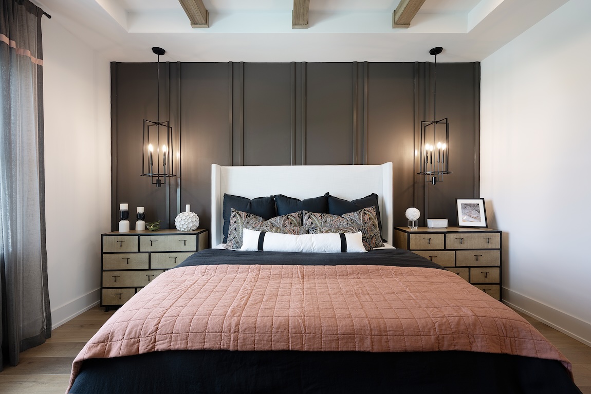 Sophisticated bedroom featuring a high-contrast palette of black and blush bedding, flanked by warm wood-toned nightstands and sculptural pendant lights against a dark accent wall.
