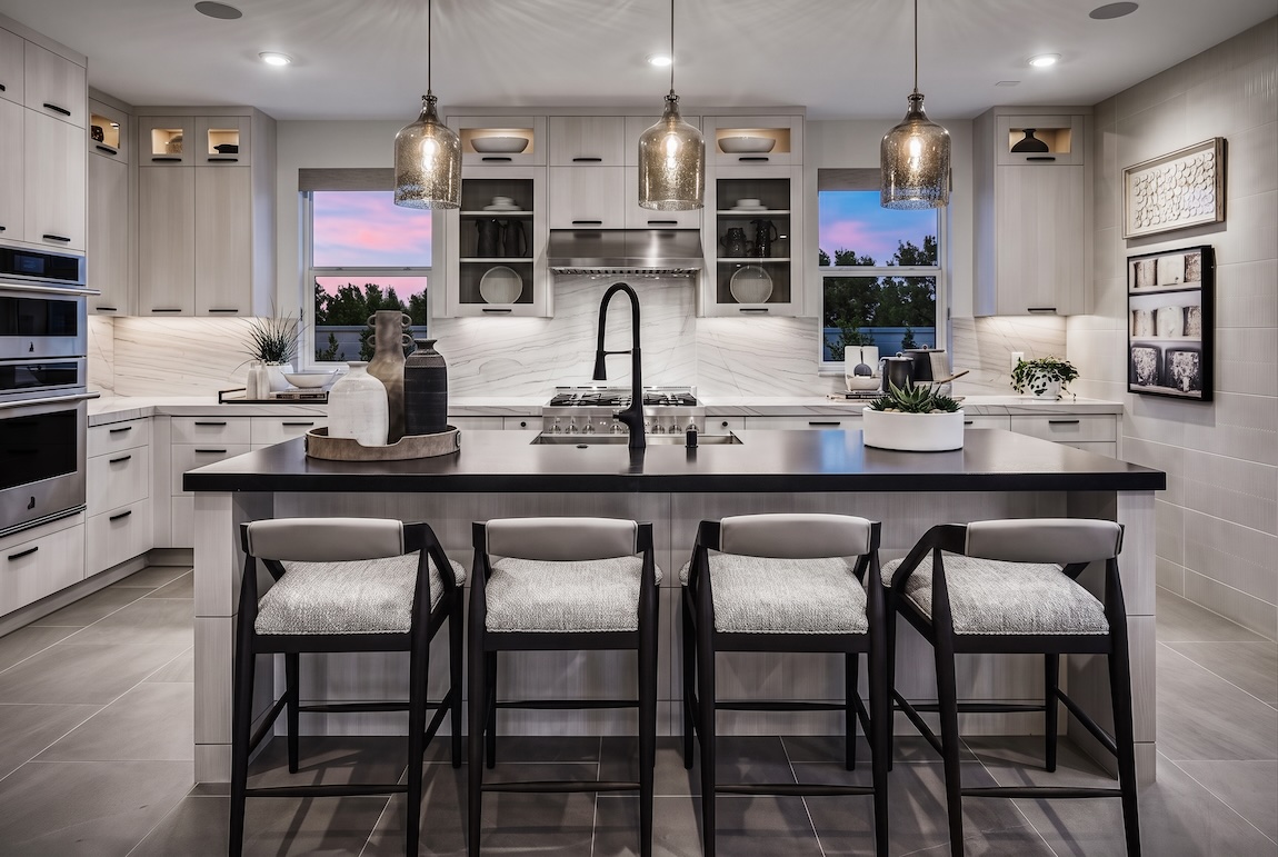 Contemporary kitchen with light cabinetry, a contrasting dark countertop island, pendant lighting, and integrated display shelving.