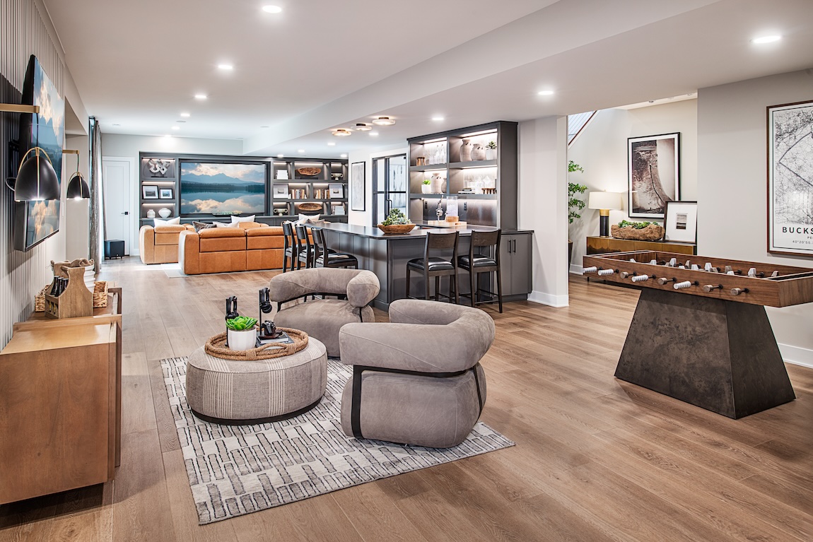 Luxury finished basement with a wet bar, lounge seating, built-in shelving, and foosball table.