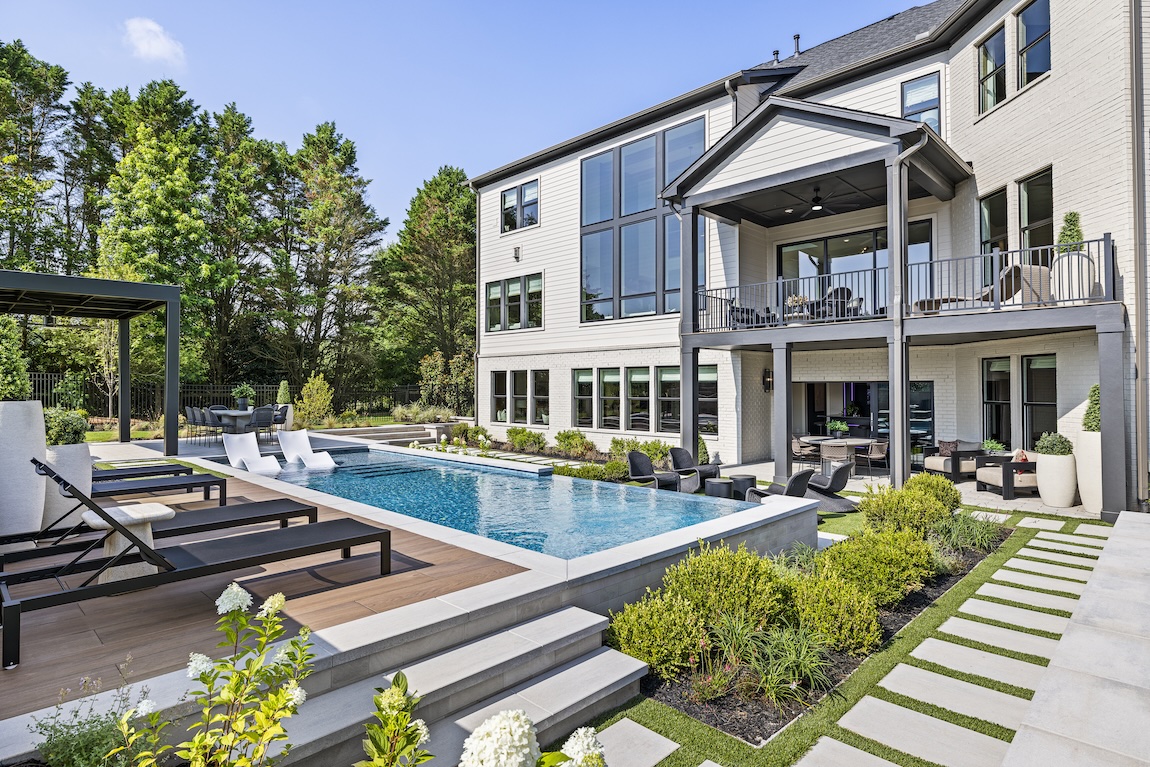 Resort-style backyard with a swimming pool, covered outdoor living spaces, sun deck, and manicured landscaping.