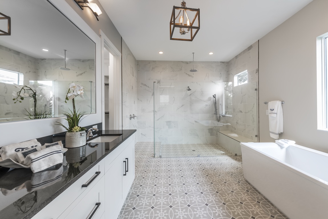 luxe white bathroom with intricate tile flooring and walk-in shower with waterfall shower head