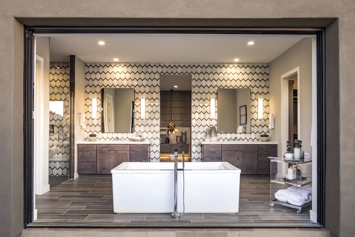 a primary bathroom with freestanding bath and outdoor transition