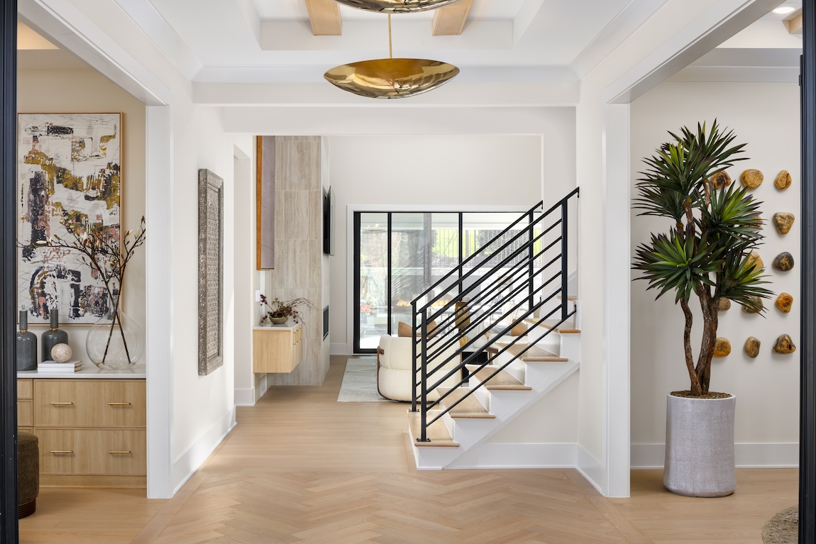 Modern foyer with herringbone floors, floating stairs, and gold ceiling accents