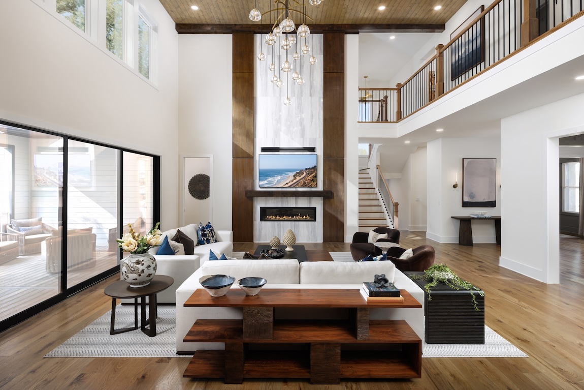 two-story great room with large chandelier and TV with fireplace.