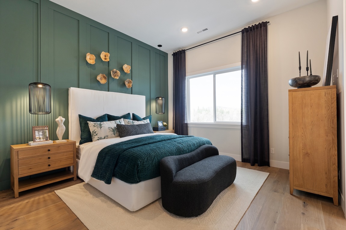 bedroom with green accent wall and curved sofa.