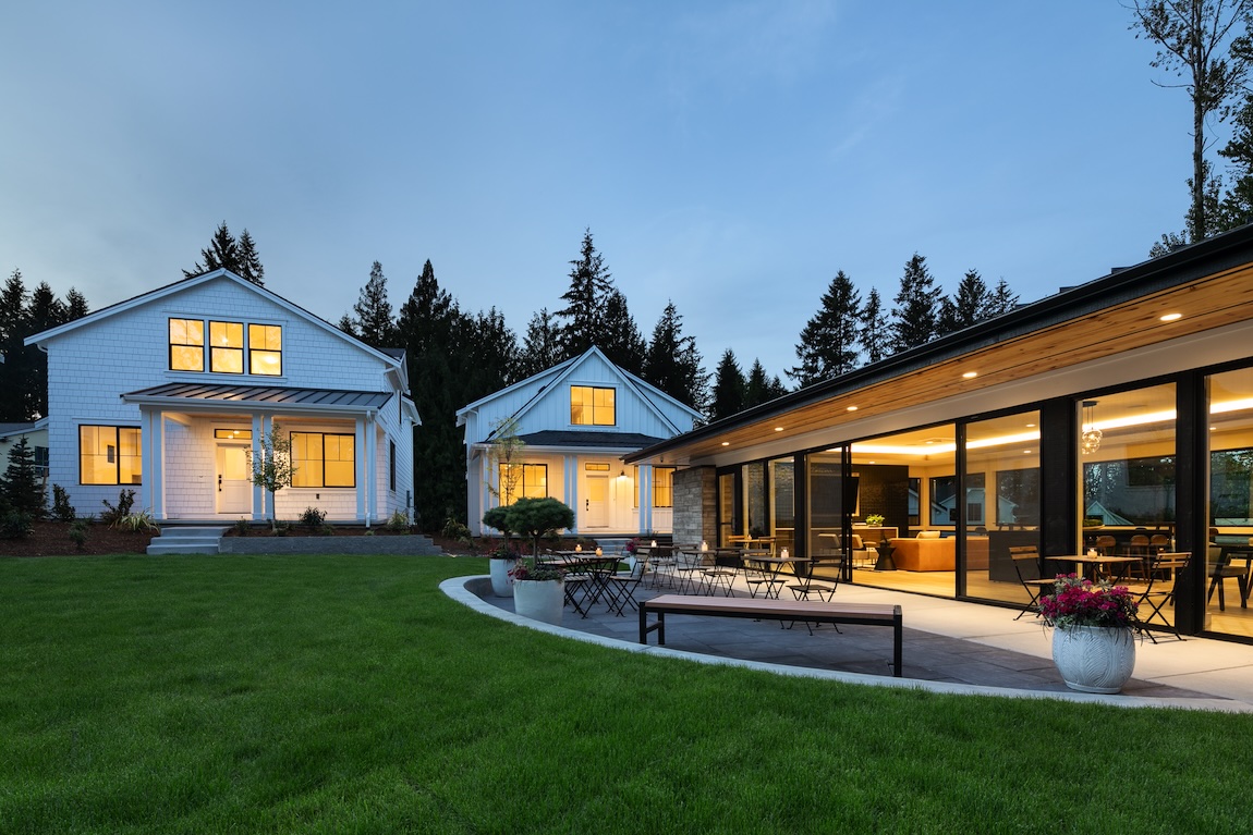 Exterior of homes and community center with warm interior lighting.