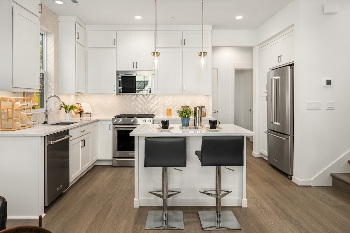 Modern kitchen with white cabinetry and a white tile backsplash.