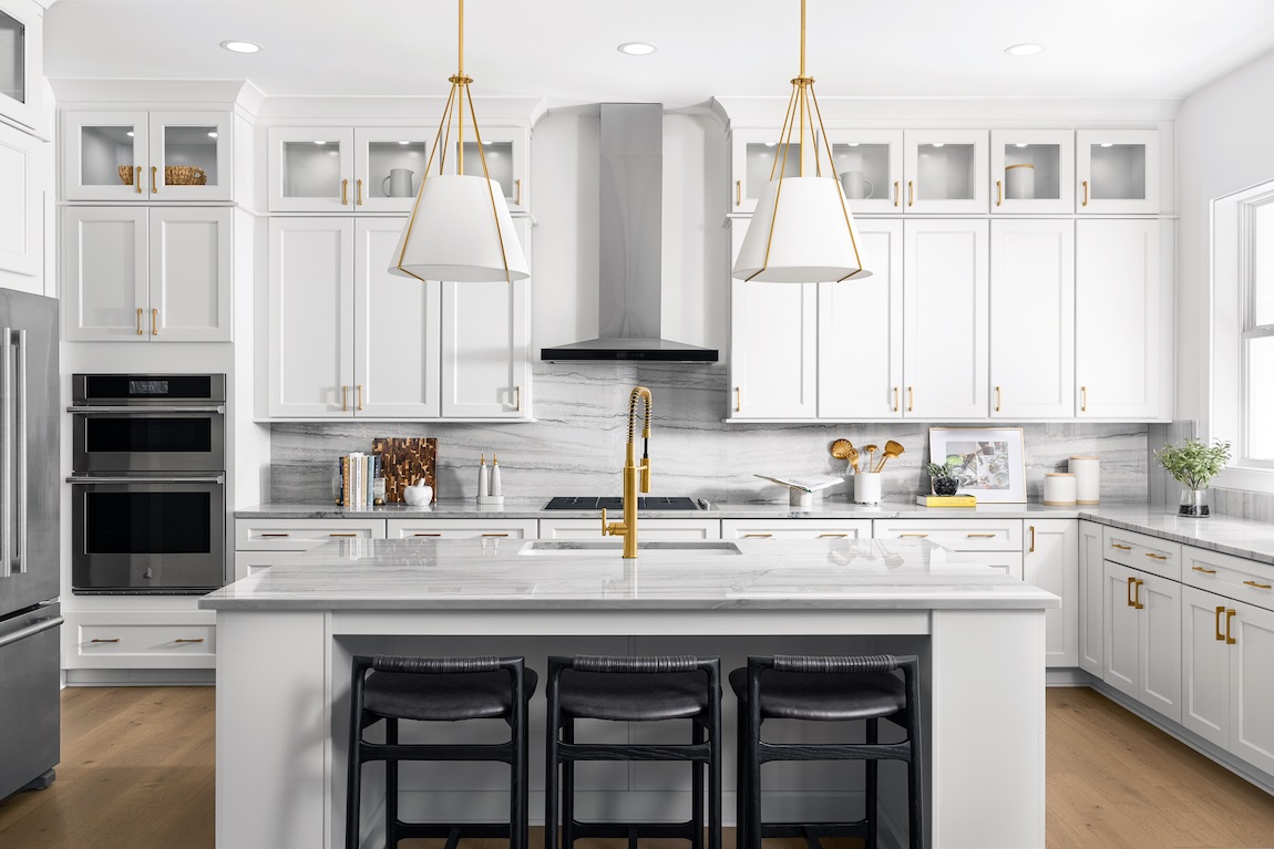 Modern kitchen with marble countertops and gold fixtures.
