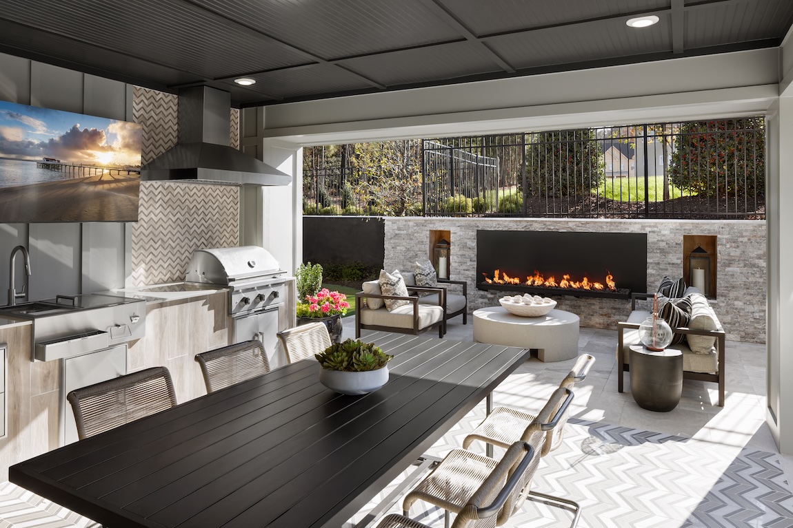 Covered outdoor patio with built-in grill and fireplace setting.