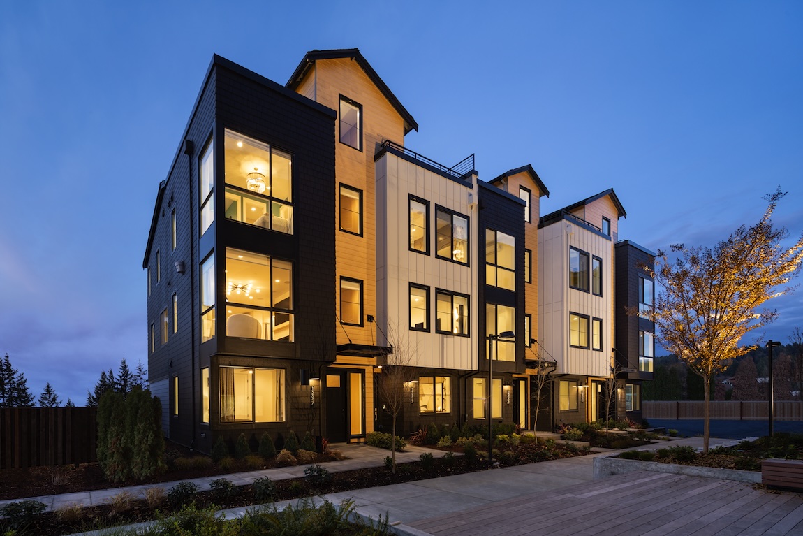 Exterior of townhomes with warm interior lighting and black and white detailing