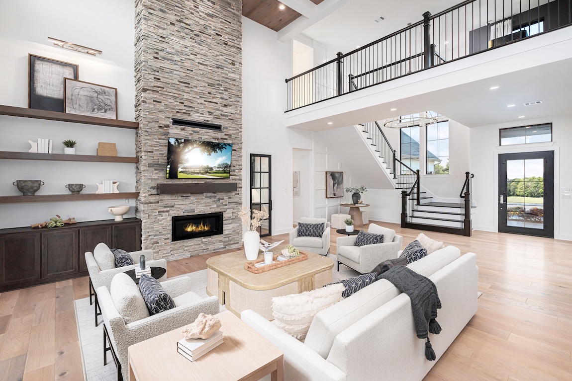 luxury open-concept living space with two-story ceiling and stone fireplace