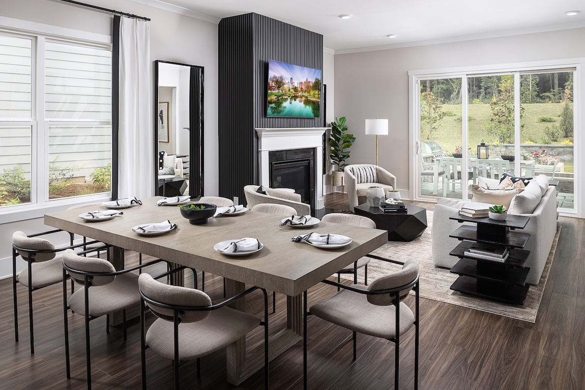 Modern dining and living area featuring a rectangular dining table, upholstered chairs, a fireplace accent wall, and large sliding doors to an outdoor space.