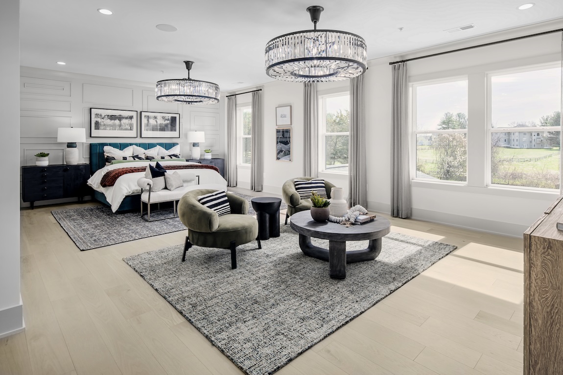 Primary bedroom with seating area and dual statement chandeliers.