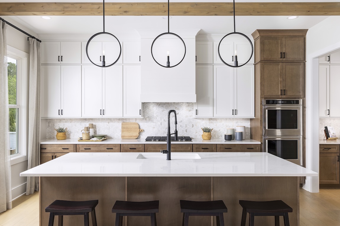 Modern kitchen with wooden and white cabinetry and pendant lights.