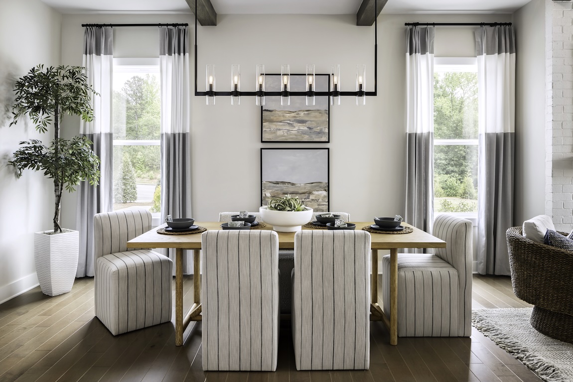 Modern dining room with wooden table and large chandelier.