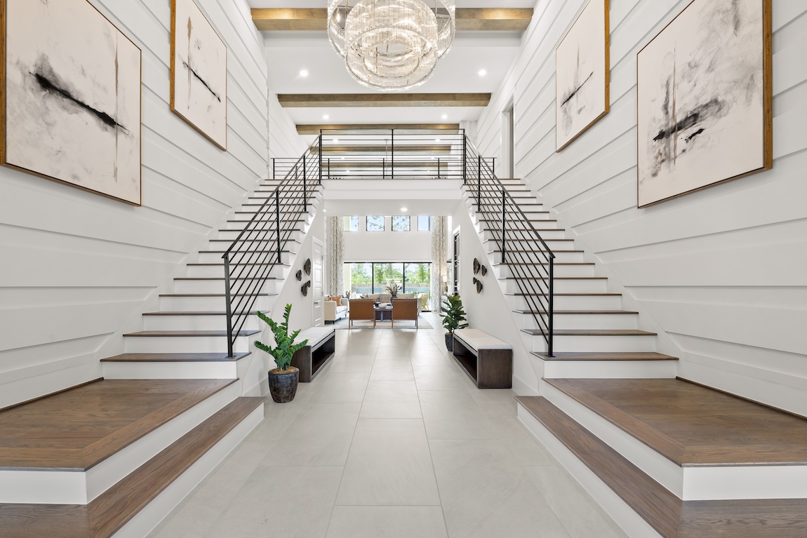 luxury entryway of home with dual staircase and views of the outdoor living space