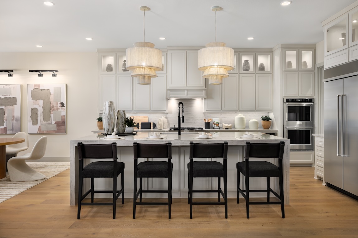 Neutral kitchen with soft white cabinetry, oversized island, and layered pendant lighting for a timeless cabinet color palette.