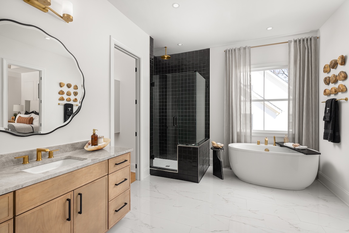 primary bathroom with freestanding tub and black tiles