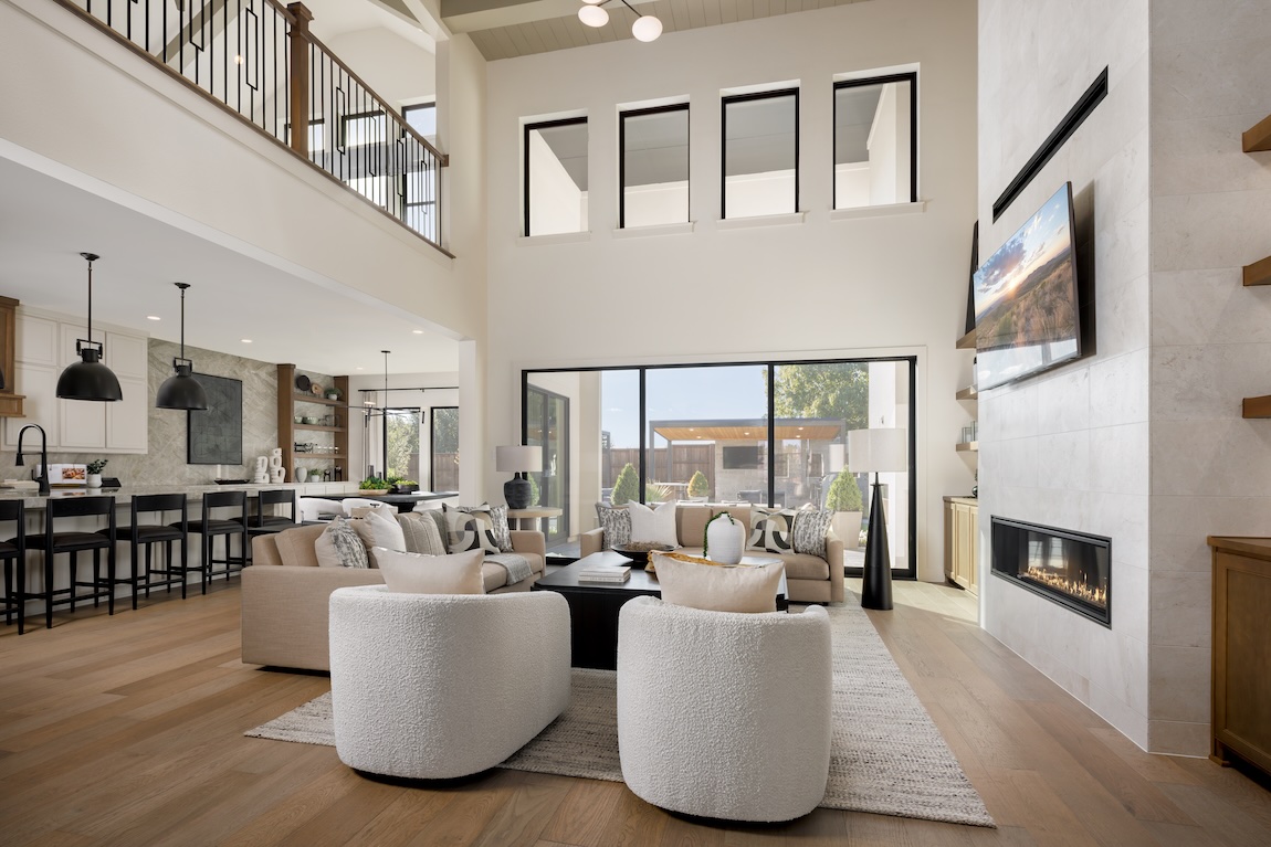 Open-concept great room with sectional seating, large windows, and walls with soft hues enhancing the warm neutral palette.