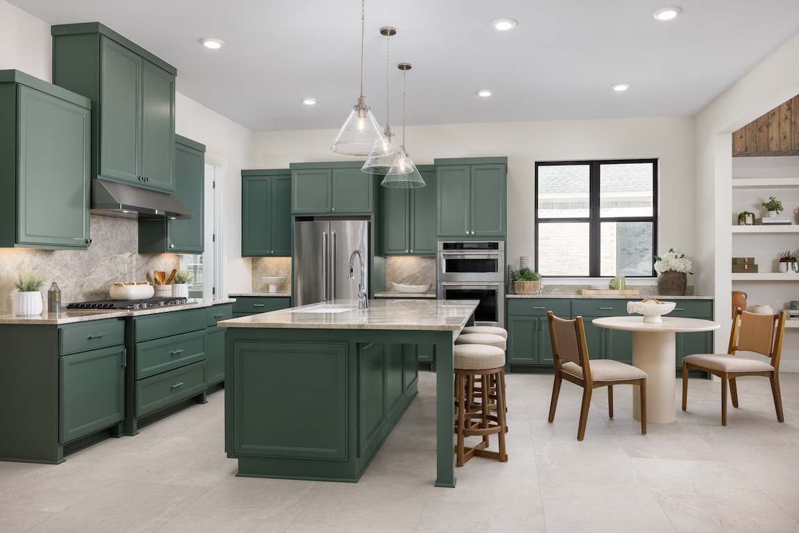 Green kitchen cabinets with silver hardware and light countertops highlighting earthy cabinet color trends.