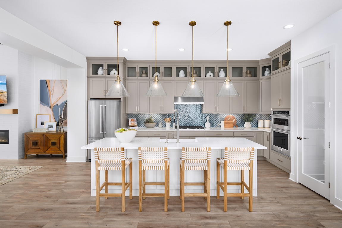 Taupe kitchen cabinets with glass uppers and blue tile backsplash offering a subtle colorful cabinet combination.
