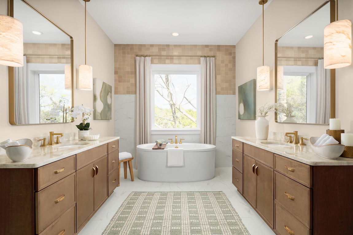 Primary bathroom with wood vanities, brass fixtures, freestanding tub, and walls painted with Universal Khaki by Sherwin-Williams for a warm spa-like feel.