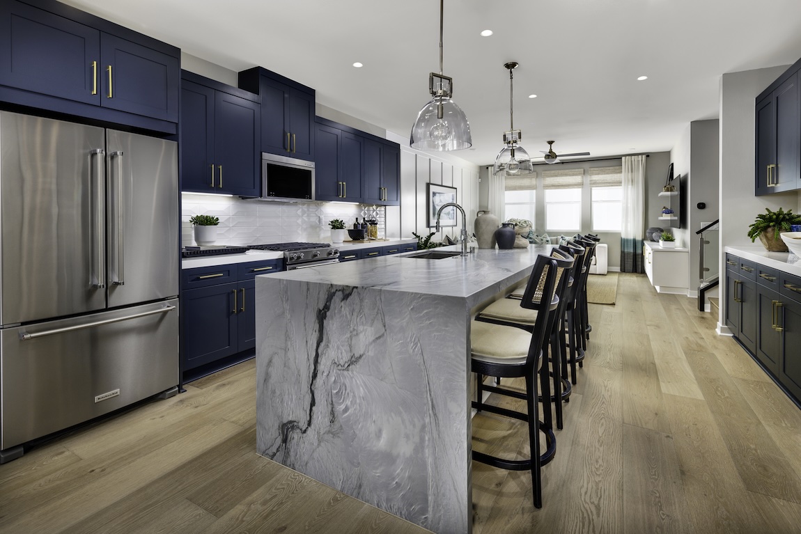 Navy blue kitchen cabinets with marble waterfall island and brass accents for a bold, modern cabinet color statement.