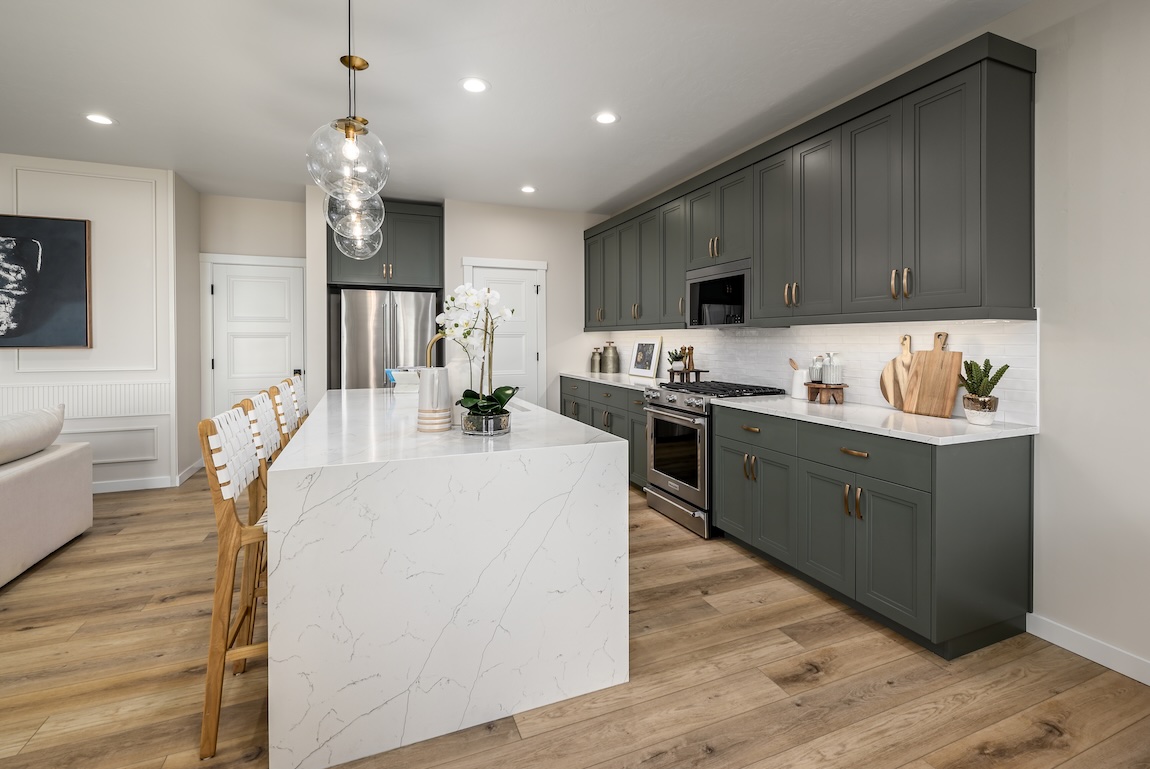 Deep charcoal kitchen cabinets with sleek island and modern lighting for dramatic cabinet color inspiration.