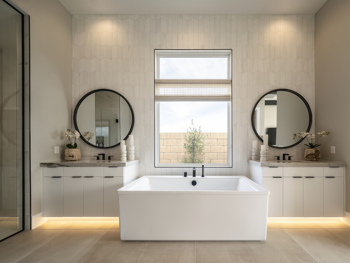 Modern primary bathroom with dual vanities, freestanding tub, and neutral walls adding soft warmth to the space.