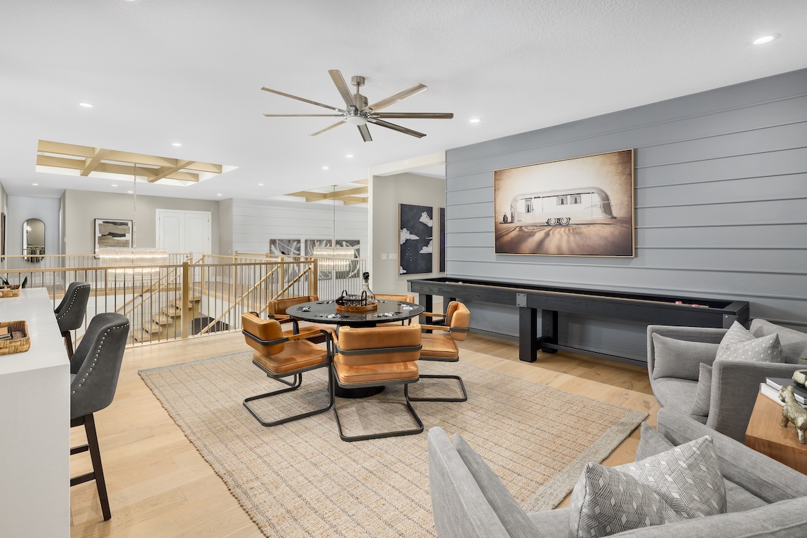 Loft living space with game table, modern seating, and neutral walls adding depth to the neutral palette.