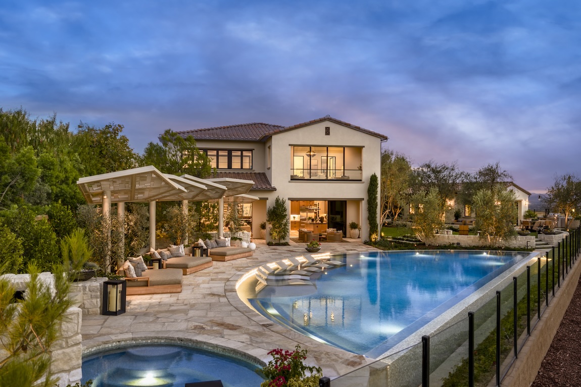 Tuscan-style home with resort-style backyard, pool, spa, and outdoor lounge area at sunset.