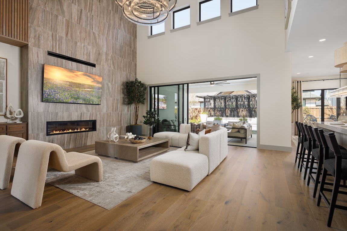 Tuscan-style great room with tall ceilings, modern fireplace wall, and seamless indoor-outdoor living design.