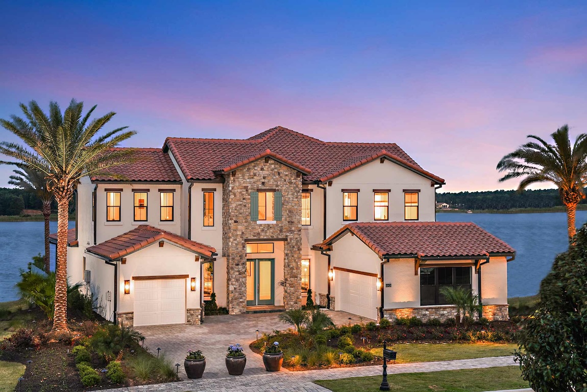 Tuscan-style home with stucco walls, stone accents, clay tile roof, and waterfront setting.