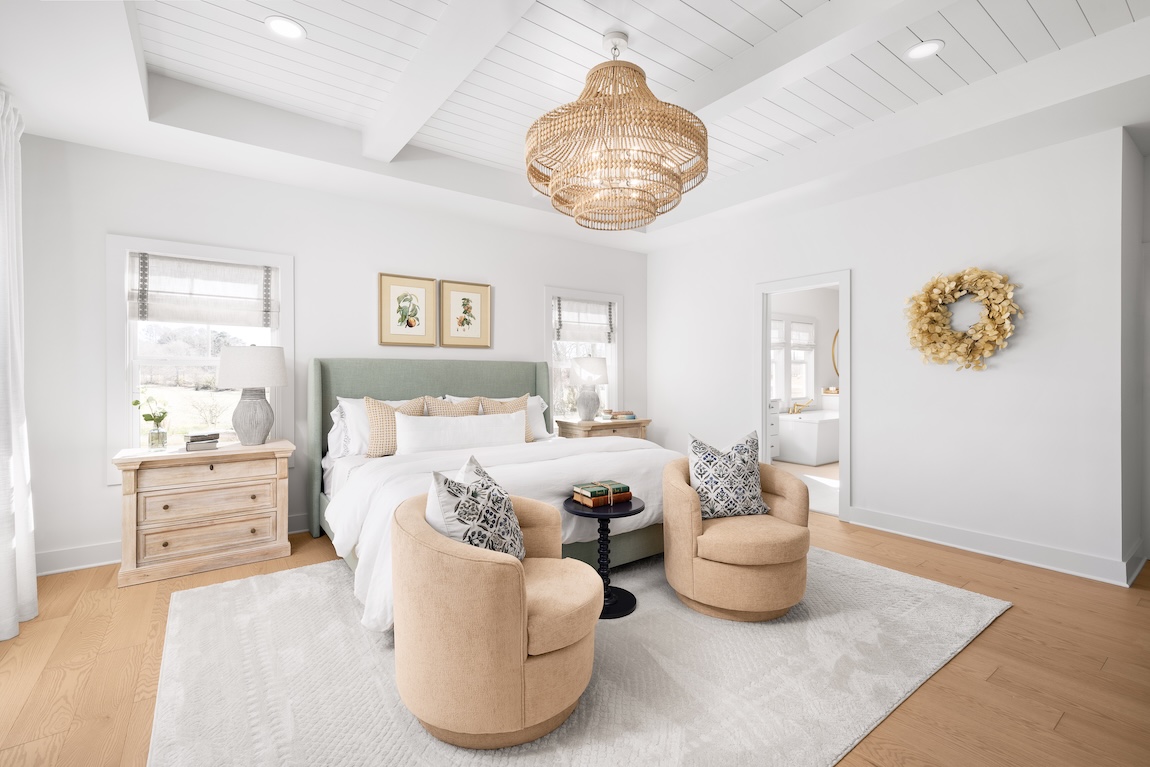 Primary bedroom with a neutral color palette and a green headboard.