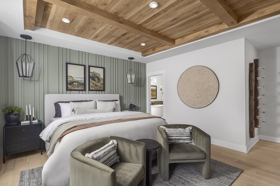 Primary bedroom with green accent wall and neutral furnishings.