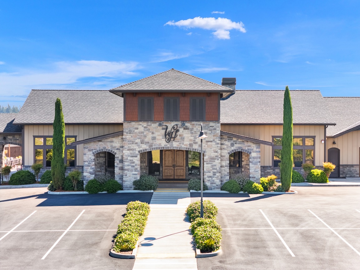 Stone clubhouse building with landscaped grounds and parking area in Ridgefield, Washington.