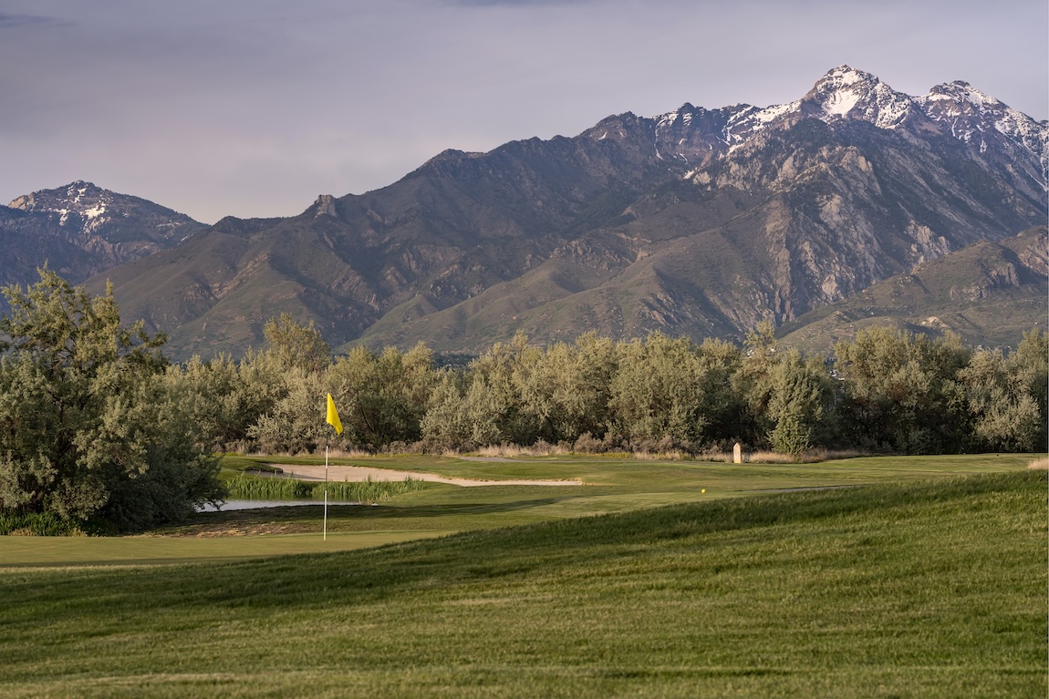 Golf course featuring manicured fairways and dramatic mountain scenery at sunset.