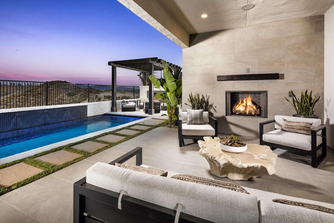 outdoor living patio with seating and fireplace next to the pool