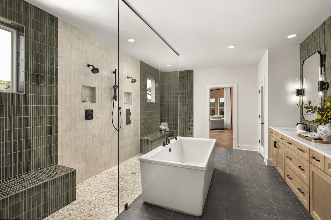 primary bathroom with green tiles and a freestanding tub