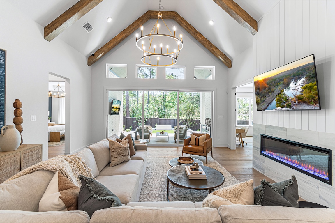 modern great room with wood beam ceilings and glass doors to the outdoors.