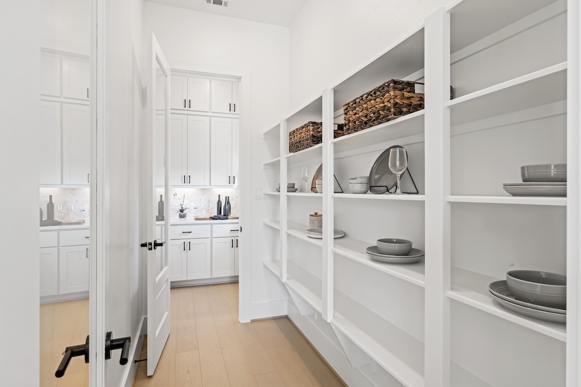 walk-in pantry with white shelving.