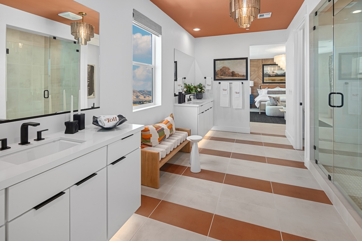 Primary bathroom with terracotta tile accents, white cabinetry, and glass-enclosed showers