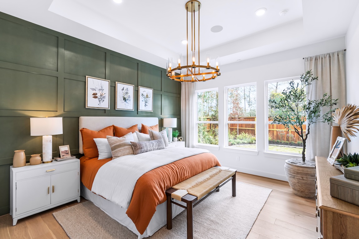 Bedroom with terracotta bedding, green paneled accent wall, and natural wood furnishings