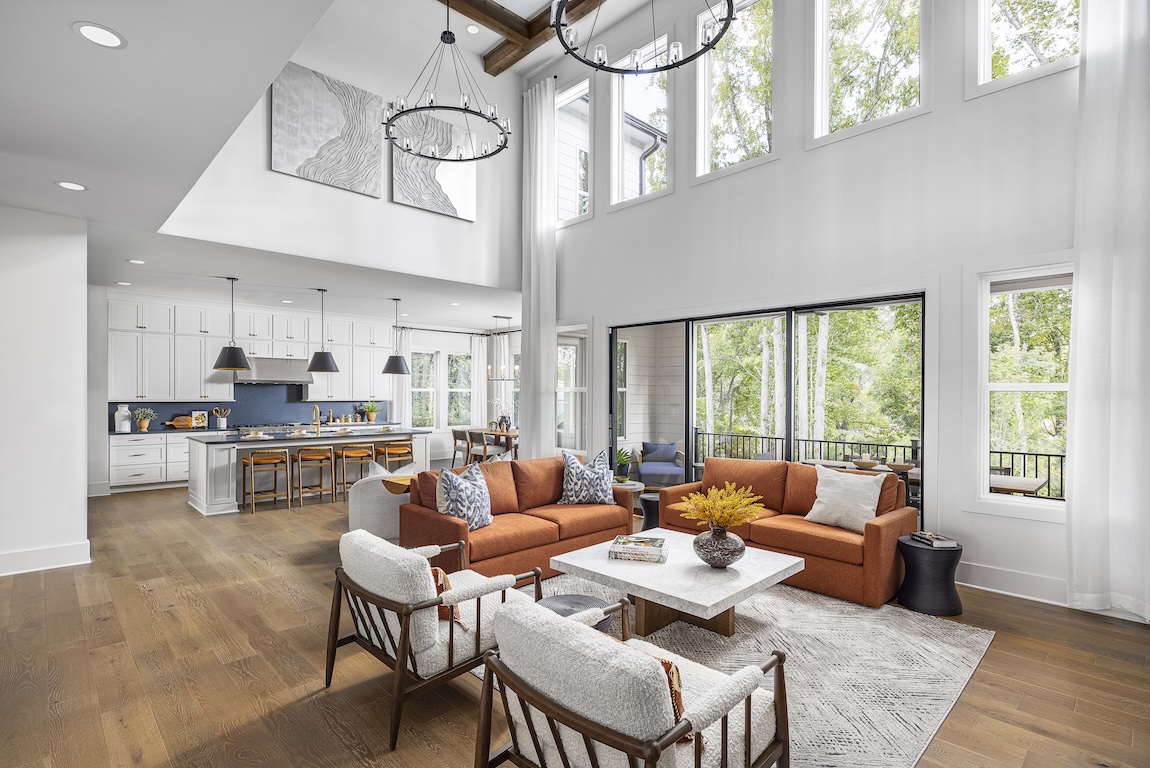 Open-concept great room with terracotta sofas, white kitchen, and expansive windows