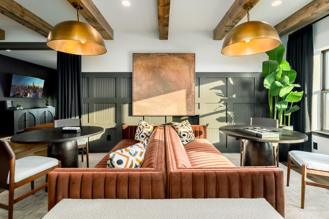 Contemporary loft with terracotta velvet seating, dark paneled walls, and brass pendant lights