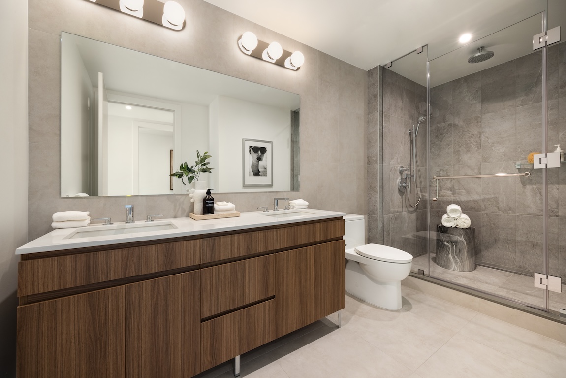 modern primary bathroom with wooden vanity and large shower