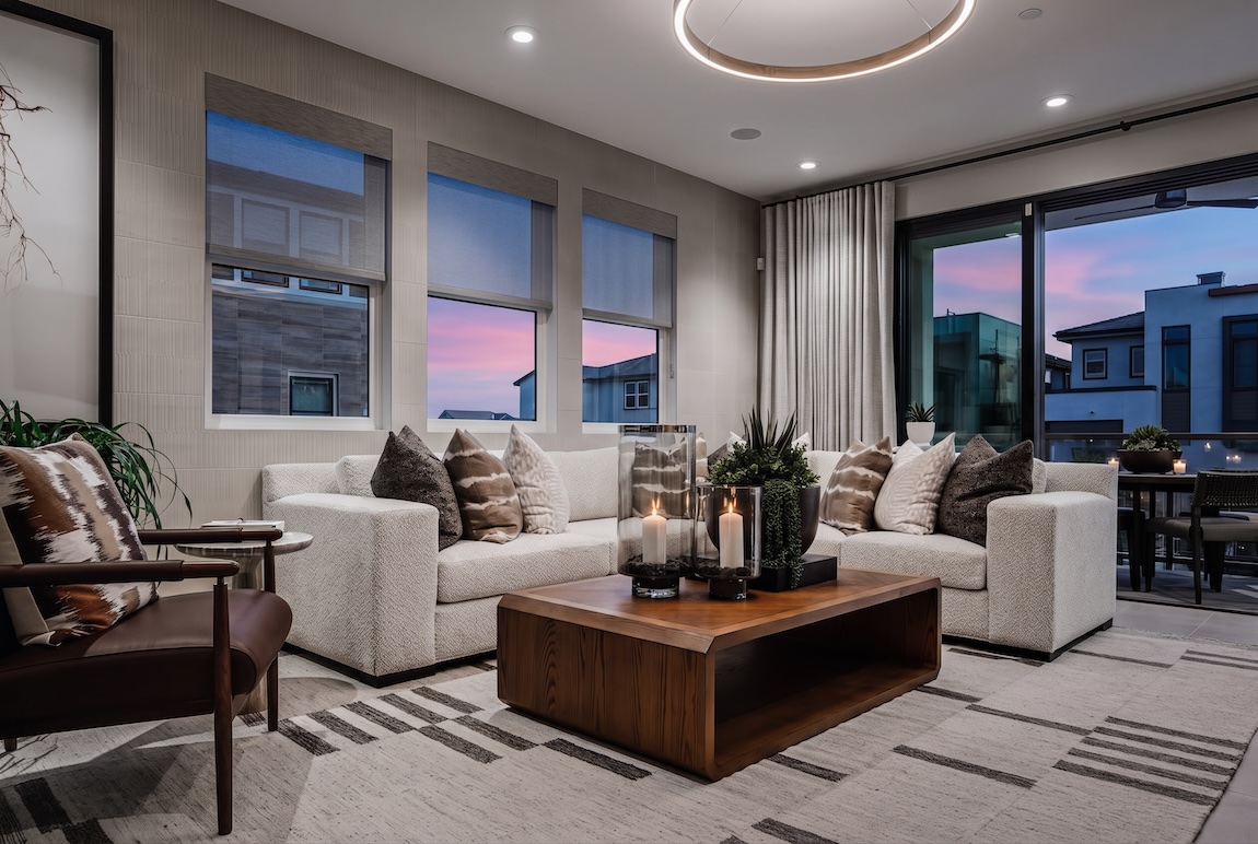 Neo Deco living room with sculptural lighting, geometric textiles, warm wood accents, and layered neutral furnishings.