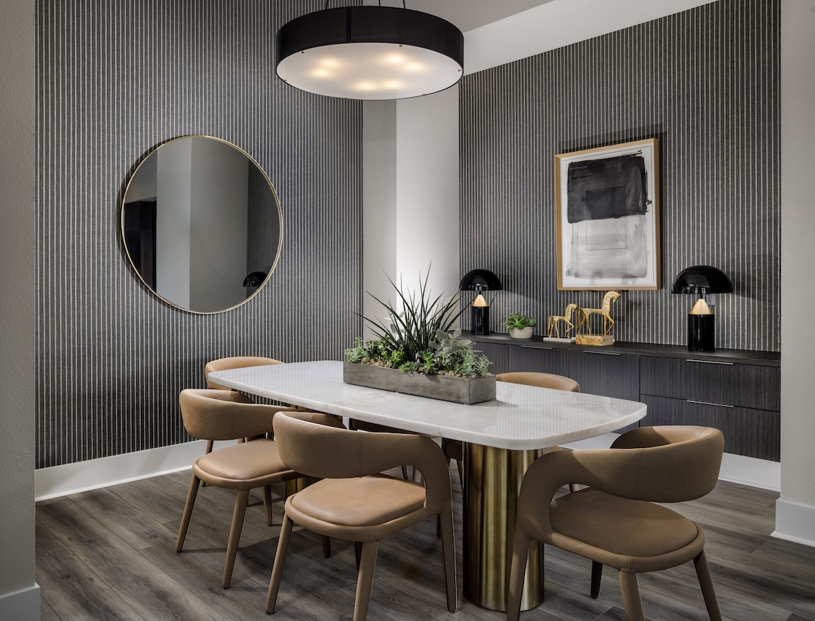 Neo Deco dining room with striped wallcovering, brass accents, curved seating, and a statement circular mirror.