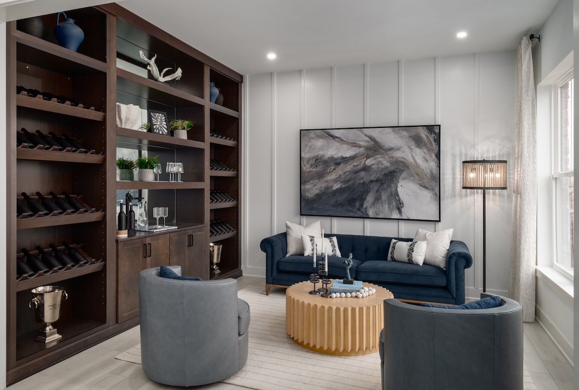 Modern lounge with built-in wine storage, curved seating, dark wood cabinetry, and metallic accents.