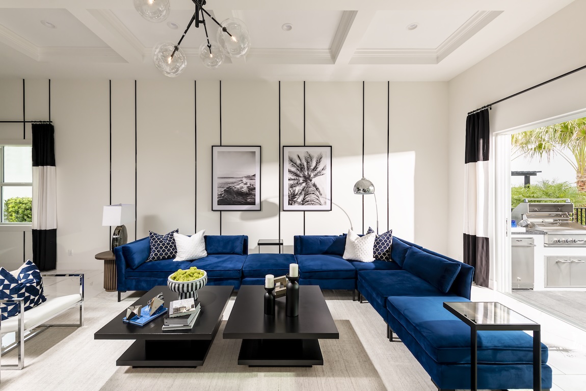 Neo Deco living room with a deep blue sectional, graphic black accents, statement artwork, and geometric detailing.